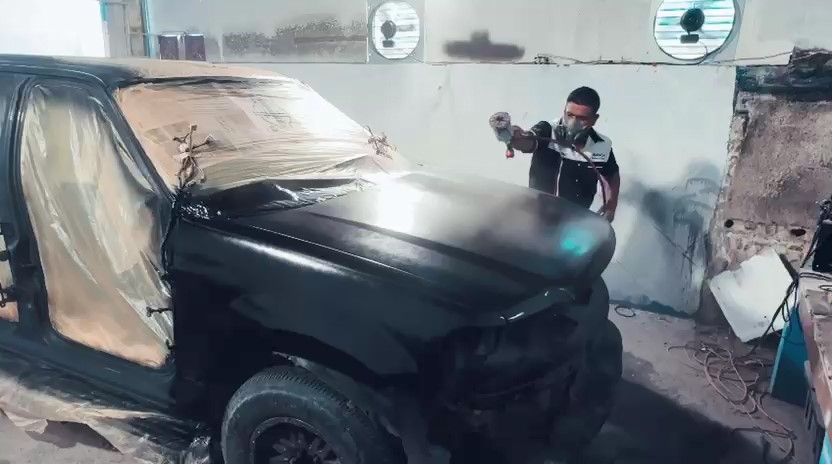 Técnico aplicando pintura a una camioneta dentro del taller
